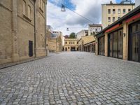 a brick road leads to several different stores in a european city with buildings behind it