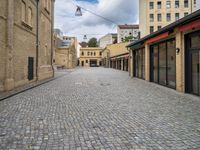 a brick road leads to several different stores in a european city with buildings behind it