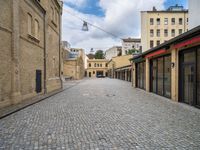 a brick road leads to several different stores in a european city with buildings behind it