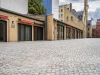 a brick road in a city with several different shops and stores on either side of each street