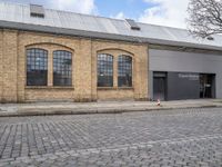 a brick road in front of a building that has two windows on it that says the company