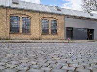 a brick road in front of a building that has two windows on it that says the company