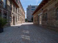 an empty street that is lined with tall brick buildings and planters in front of it