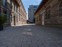 an empty street that is lined with tall brick buildings and planters in front of it