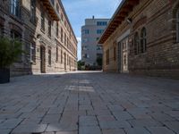 an empty street that is lined with tall brick buildings and planters in front of it