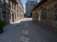 an empty street that is lined with tall brick buildings and planters in front of it