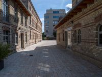 an empty street that is lined with tall brick buildings and planters in front of it