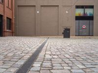 a paved, brick street lined with shops with brown doors and signs on the wall