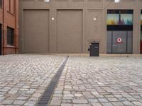 a paved, brick street lined with shops with brown doors and signs on the wall