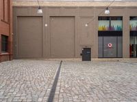 a paved, brick street lined with shops with brown doors and signs on the wall