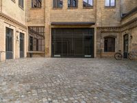 a cobblestone courtyard with a bicycle leaned up against a rail near a brick building