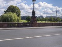 the bridge crosses over a busy highway and there is an ornamentally decorated fence with statues