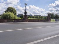 the bridge crosses over a busy highway and there is an ornamentally decorated fence with statues