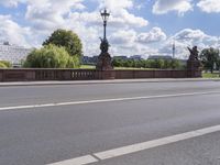 the bridge crosses over a busy highway and there is an ornamentally decorated fence with statues