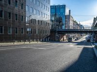 the empty city street near some modern buildings in europe during the day with sunlight on the building roof