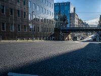 the empty city street near some modern buildings in europe during the day with sunlight on the building roof