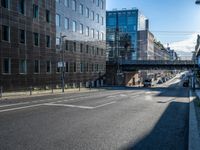 the empty city street near some modern buildings in europe during the day with sunlight on the building roof