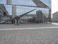 the building is reflecting in the windows on the outside and a stone sidewalk in between it