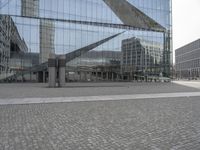 the building is reflecting in the windows on the outside and a stone sidewalk in between it