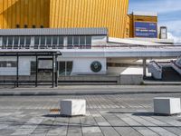 a empty sidewalk at an airport with benches near the walkway and stairs leading up to the terminal