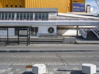 a empty sidewalk at an airport with benches near the walkway and stairs leading up to the terminal