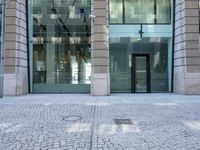 a building with stone walkway and glass walls with double doors on both sides of the entrance