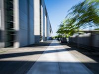 the picture is of a long sidewalk outside of a building, looking blurry at one end