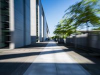 the picture is of a long sidewalk outside of a building, looking blurry at one end