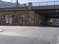 a bus going under a bridge near a road full of graffiti and graffiti art on the wall