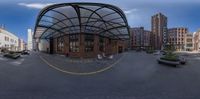 a wide angle shot taken through a fisheye lens of a bus stop building near the street