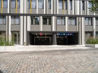 two buildings with a parking garage under one roof and a sidewalk in front of them