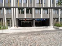 two buildings with a parking garage under one roof and a sidewalk in front of them