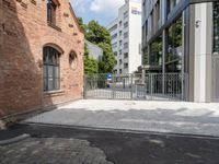 an empty sidewalk in front of a building and a gate with a blue sign on it