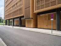 an empty street and an intersection sign in front of brown building with black windows on both sides