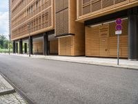 an empty street and an intersection sign in front of brown building with black windows on both sides