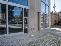 the entrance to a building on a street corner next to large windows with multiple pictures on them