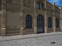 the sidewalk is paved with stones and has a bench in front of it, with no people inside