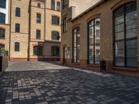 a sidewalk with chairs next to the brick building on the side, some have stairs and some buildings in the background