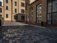 a sidewalk with chairs next to the brick building on the side, some have stairs and some buildings in the background