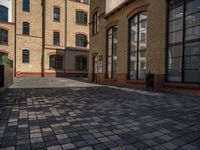 a sidewalk with chairs next to the brick building on the side, some have stairs and some buildings in the background