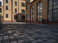 a sidewalk with chairs next to the brick building on the side, some have stairs and some buildings in the background