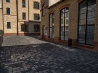 a sidewalk with chairs next to the brick building on the side, some have stairs and some buildings in the background