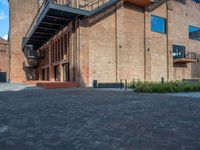 the red brick building has a wrought iron railing over it's roof, and on the left side it is a red brick wall