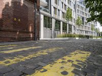 the sidewalk has yellow paint on it and an empty building in the background with trees