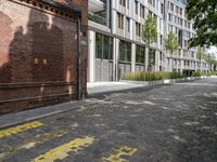 the sidewalk has yellow paint on it and an empty building in the background with trees