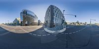 the curved glass building is on the corner at the intersection of a street, and a car is driving in