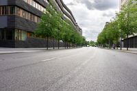 an empty street with several buildings on both sides, and trees planted along the side