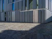 cobblestone driveway surrounded by modern buildings on sunny day with sun reflecting onto the windows