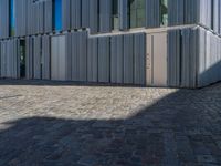 cobblestone driveway surrounded by modern buildings on sunny day with sun reflecting onto the windows