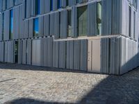 cobblestone driveway surrounded by modern buildings on sunny day with sun reflecting onto the windows